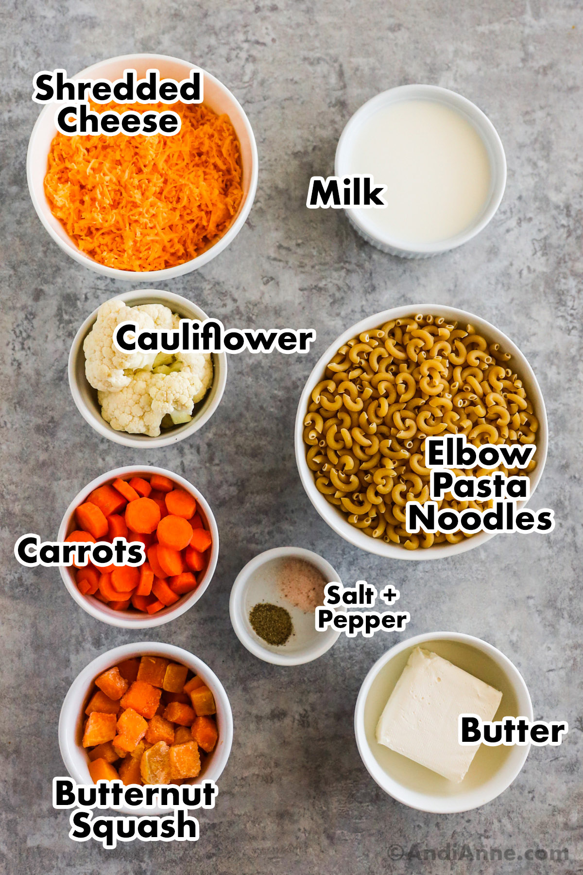 Recipe ingredients including bowls of shredded cheese, milk, cauliflower, pasta, carrots, squash, butter, salt and pepper