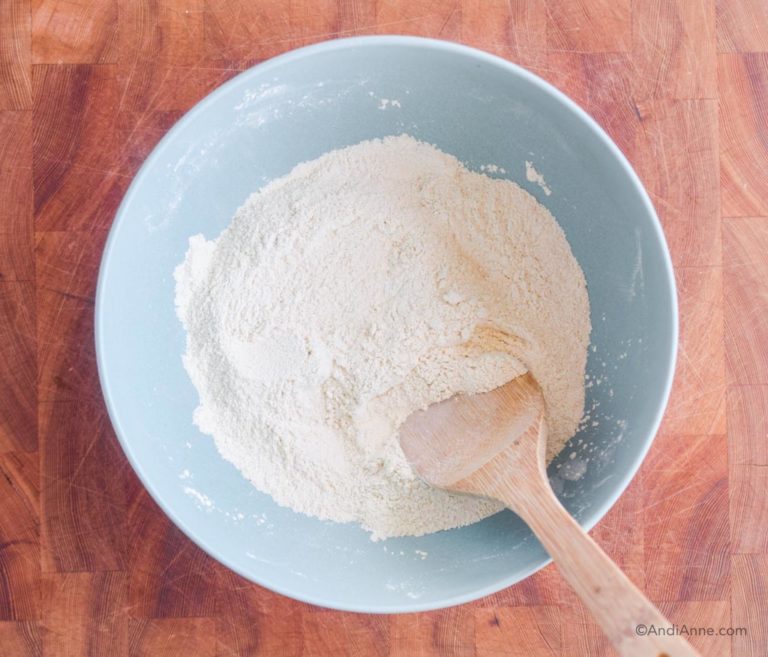 white quinoa flour in a blue bowl with a wooden spoon