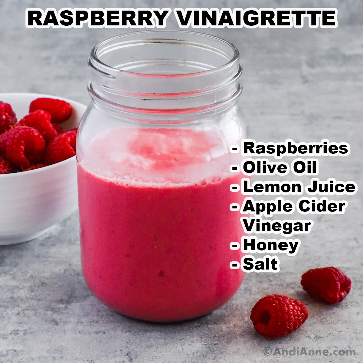 A mason jar of raspberry vinaigrette with a bowl of fresh raspberries and a list of ingredients including raspberries, olive oil, lemon juice, apple cider vinegar, honey and salt.