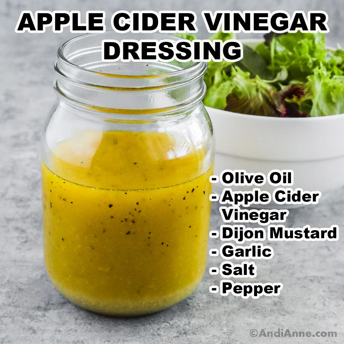 A jar of apple cider vinegar dressing with ingredients including olive oil, apple cider vinegar, dijon mustard, garlic, salt and pepper.