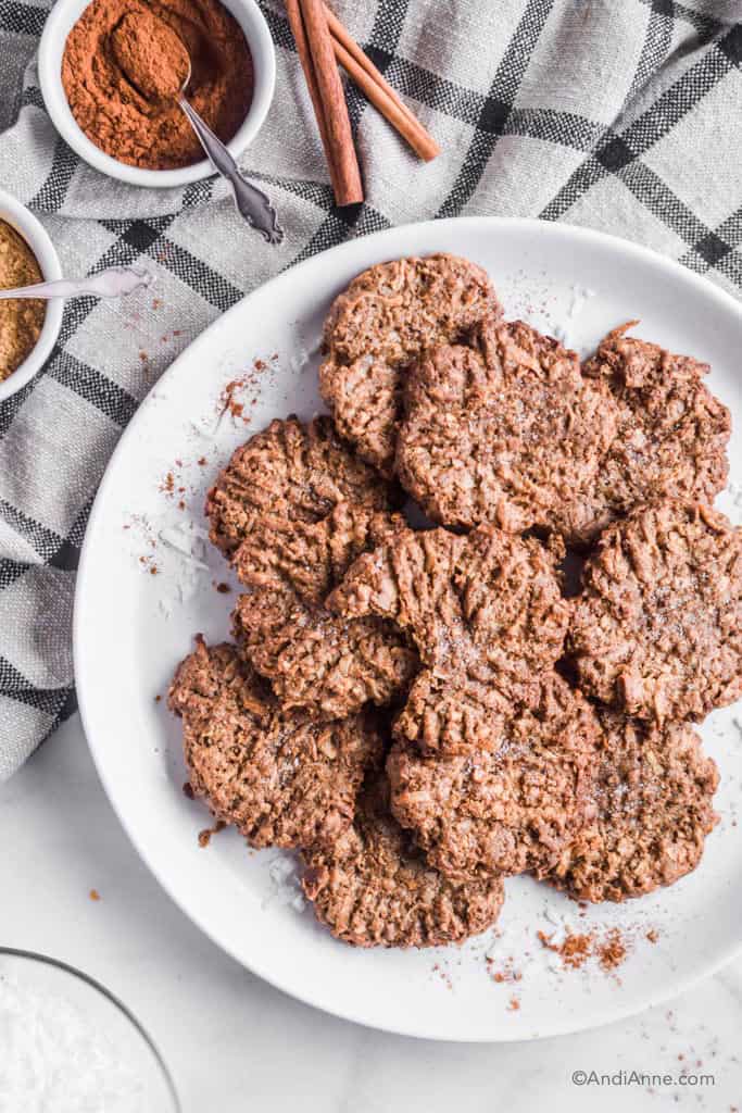 coconut cinnamon ginger cookies on a plate with kitchen towel and bowls of spices beside it