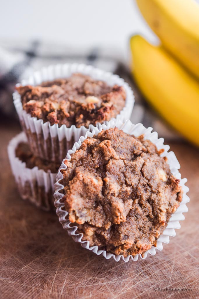 coconut flour banana muffins stacked together with bananas in the background.