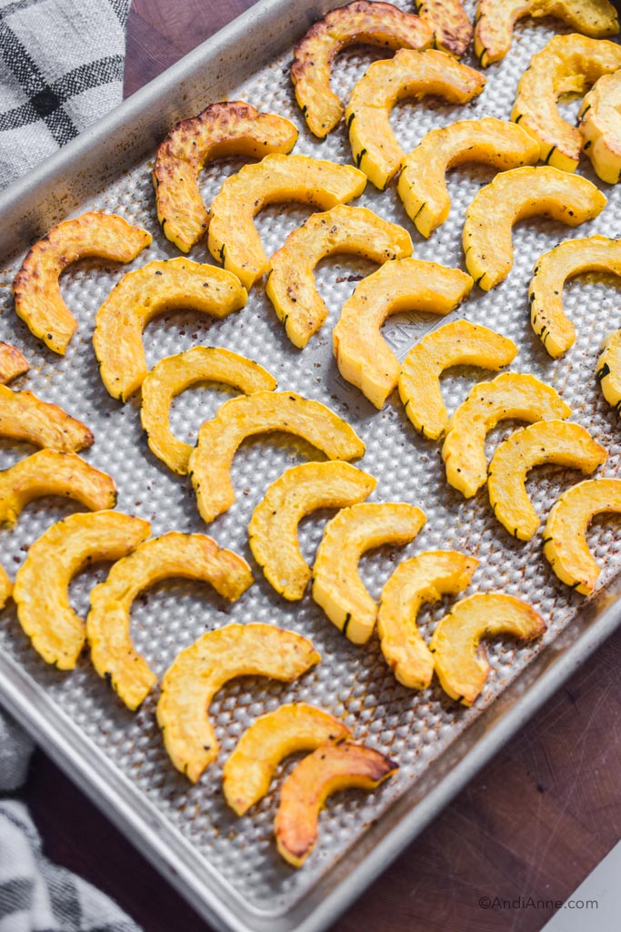 cooked and sliced delicata squash on a baking sheet 