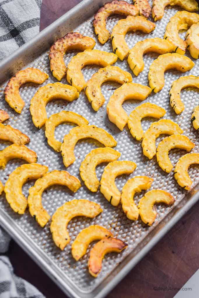 cooked and sliced delicata squash on a baking sheet 