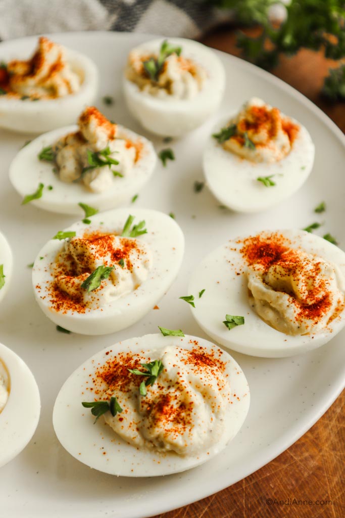 Close up of deviled eggs sprinkled with paprika on a white plate.