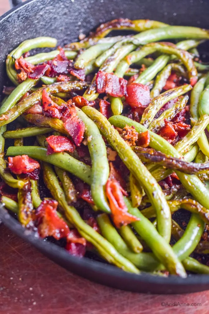 close up of cooked green beans and bacon in black frying pan