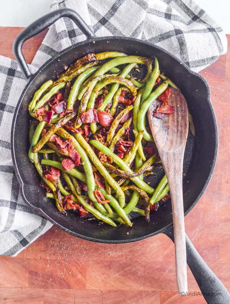 green beans and chopped bacon in a black skillet with wooden spoon - healthy holiday recipes
