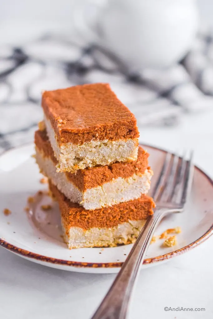 three pumpkin pie bars stacked on top of eachother on a white plate 