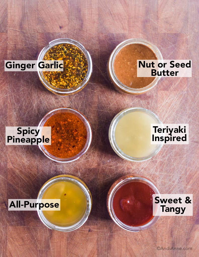 six healthy stir fry sauce combinations including ginger garlic, nut or seed butter, spicy pineapple, teriyaki inspired, all purpose and sweet and tangy in glass jars on a wood counter
