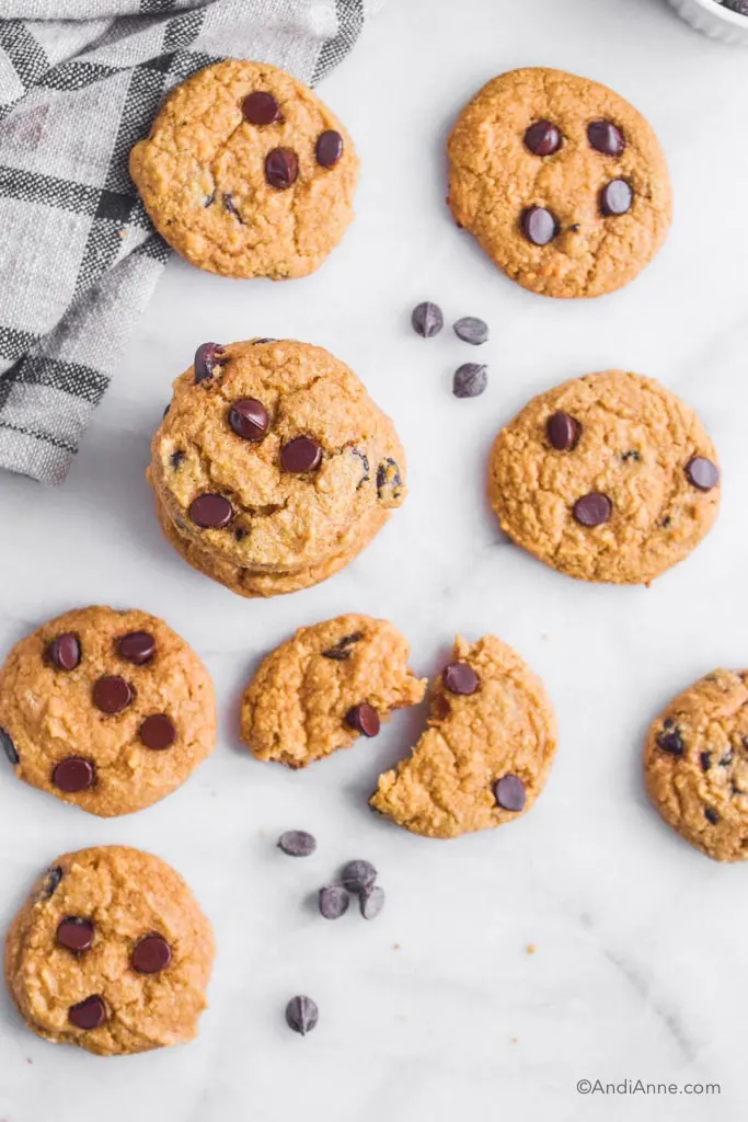 chickpea chocolate chip cookies on a white marble counter with a few chocolate chips and kitchen towel.