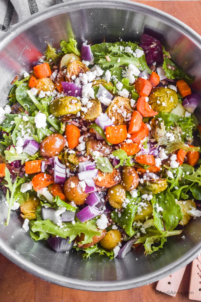 Roasted vegetable wild rice salad in steel bowl with feta cheese sprinkled over top.