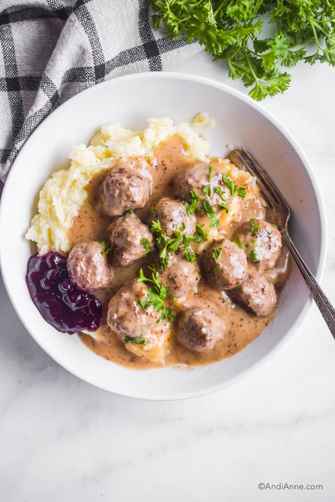 swedish meatballs with mashed potatoes and lingonberry jam in a white bowl.