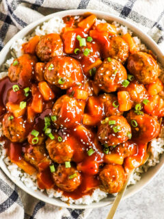 A plate of sweet and sour meatballs with rice