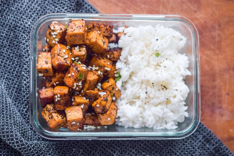 A glass dish with half white rice and other half cooked cubed tofu.