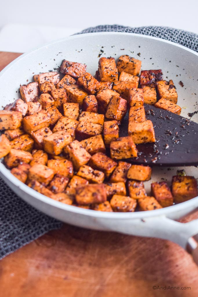 cooked tofu in a frying pan with wood spatula