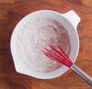 dry ingredients in white bowl with red whisk