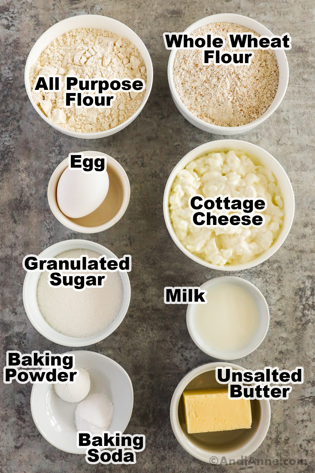 Bowls of recipe ingredients including all purpose flour, whole wheat flour, an egg, cottage 