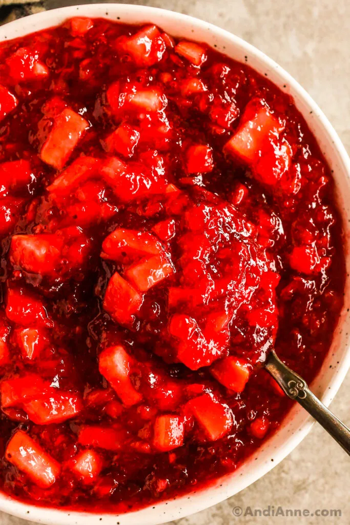 A bowl of cranberry jello salad with a spoon.