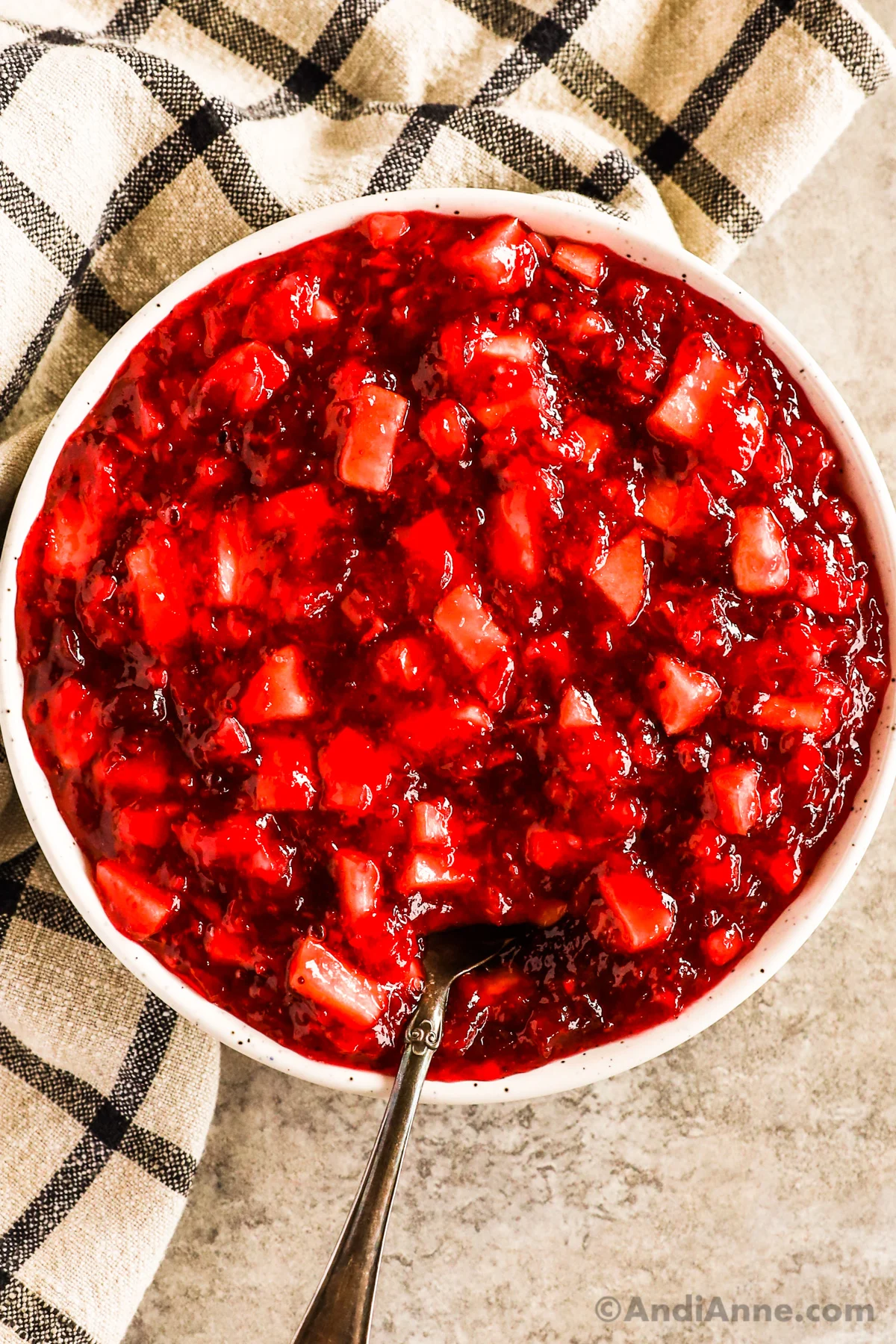 A bowl of pineapple cranberry jello salad with chopped apple.