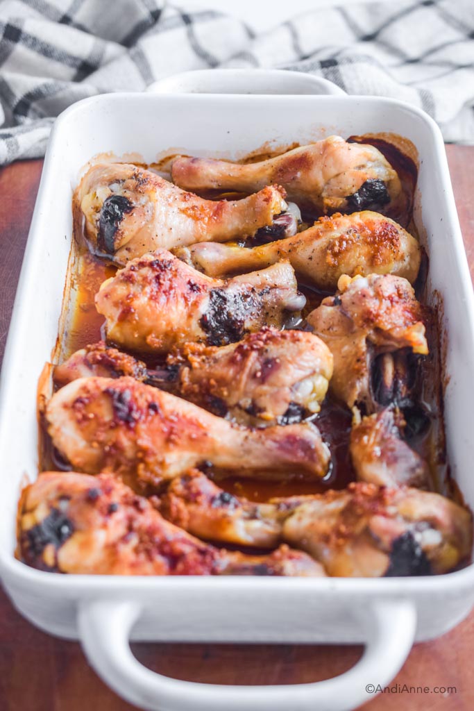 side angle of chicken legs with ginger garlic sauce in a white casserole dish.