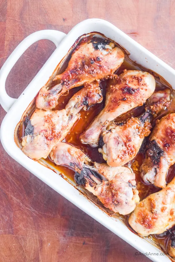 ginger garlic chicken legs in a white baking dish with a handle on a butcher block.