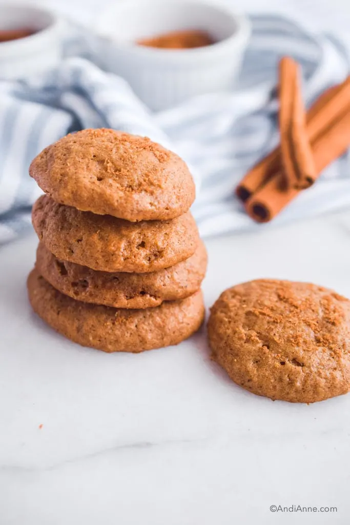 stacked applesauce spice cookies with kitchen towel and cinnamon sticks in background.