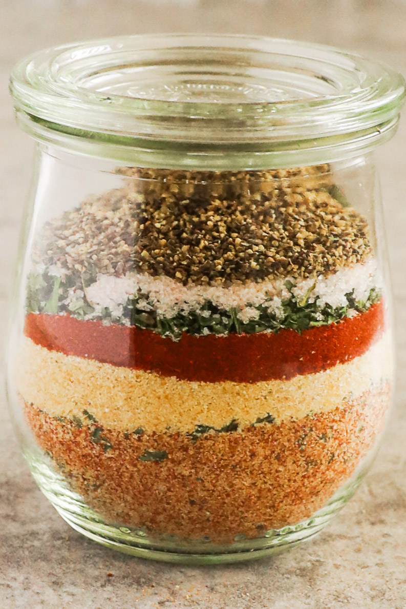 Close up of layers of different spices in a spice jar.