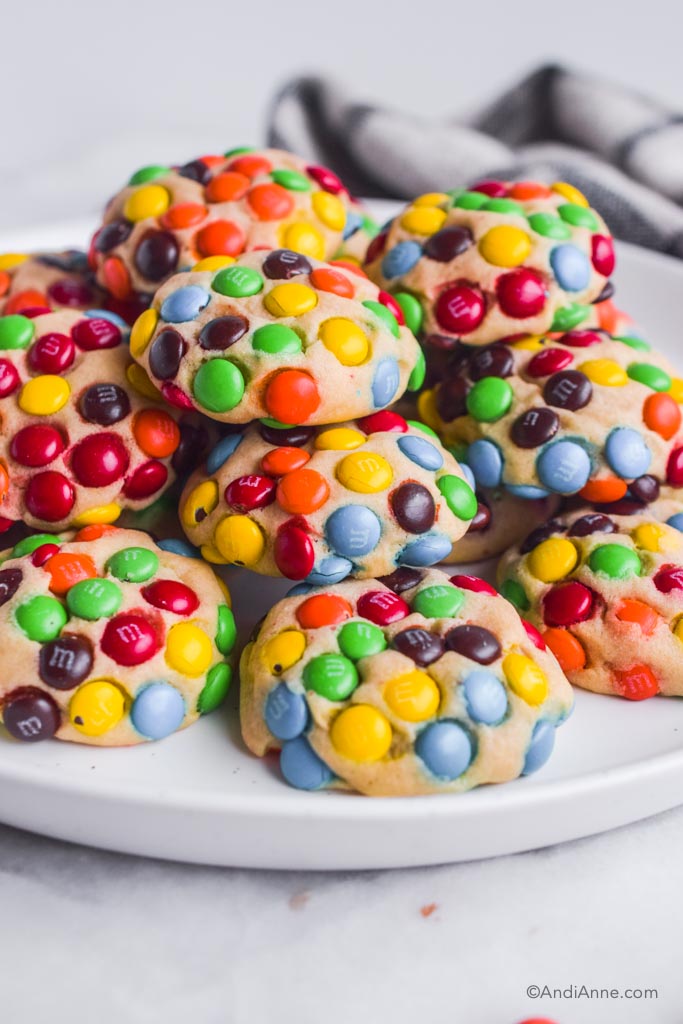 Mini M&Ms cookies stacked on a white plate.