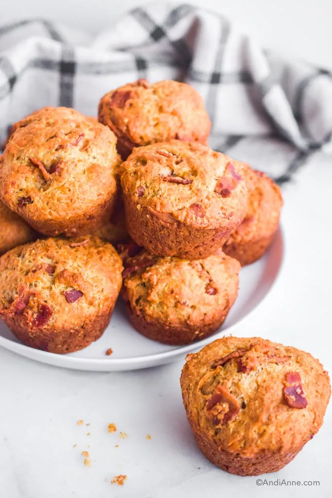 bacon cheese muffin biscuits piled on a white plate with one in front.