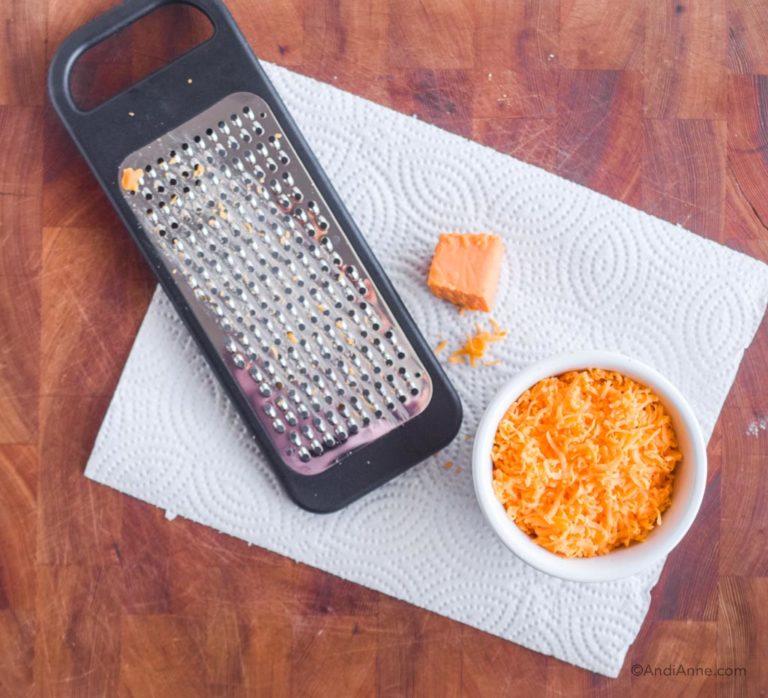 cheese grater, paper towel and bowl with shredded cheese