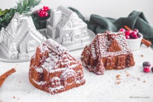 two gingerbread cakes sprinkled with confectioners sugar. Nordicware pan and christmas decorations in background.