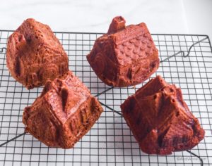 4 gingerbread house cakes on a black cooling rack
