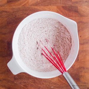 white bowl of flour with red whisk