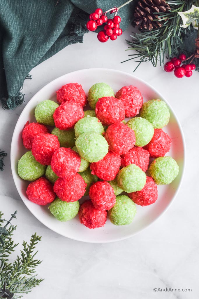 red and green jello balls on a white plate with fake greenery surround it. 