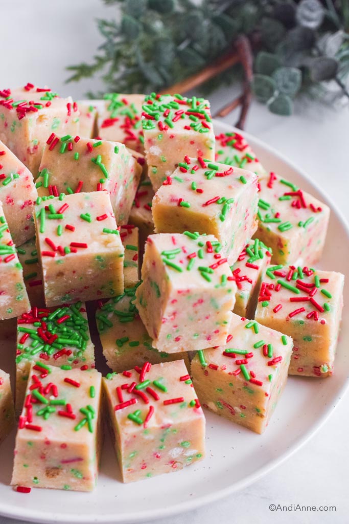 sugar cookie fudge squares with green and red jimmies stacked on a white plate.