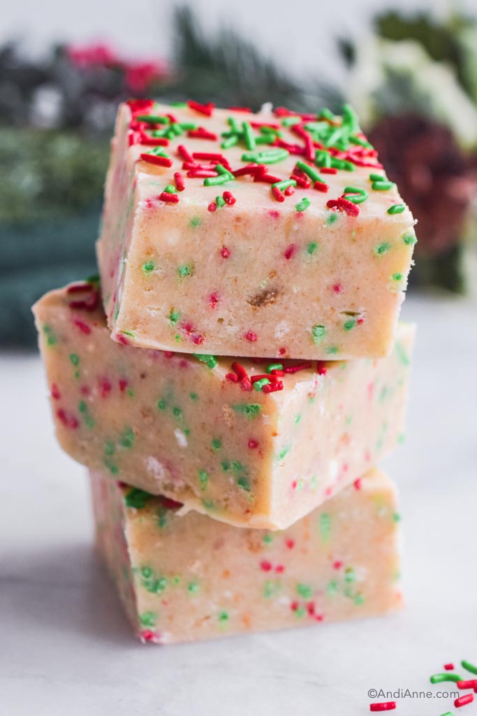 Three sugar cookie fudge squares stacked on top of eachother with red and green sprinkles on top.