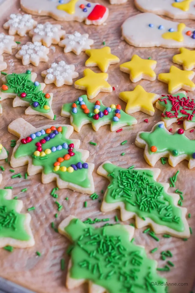 Side angle of decorated christmas sugar cookies on baking sheet with parchment paper.