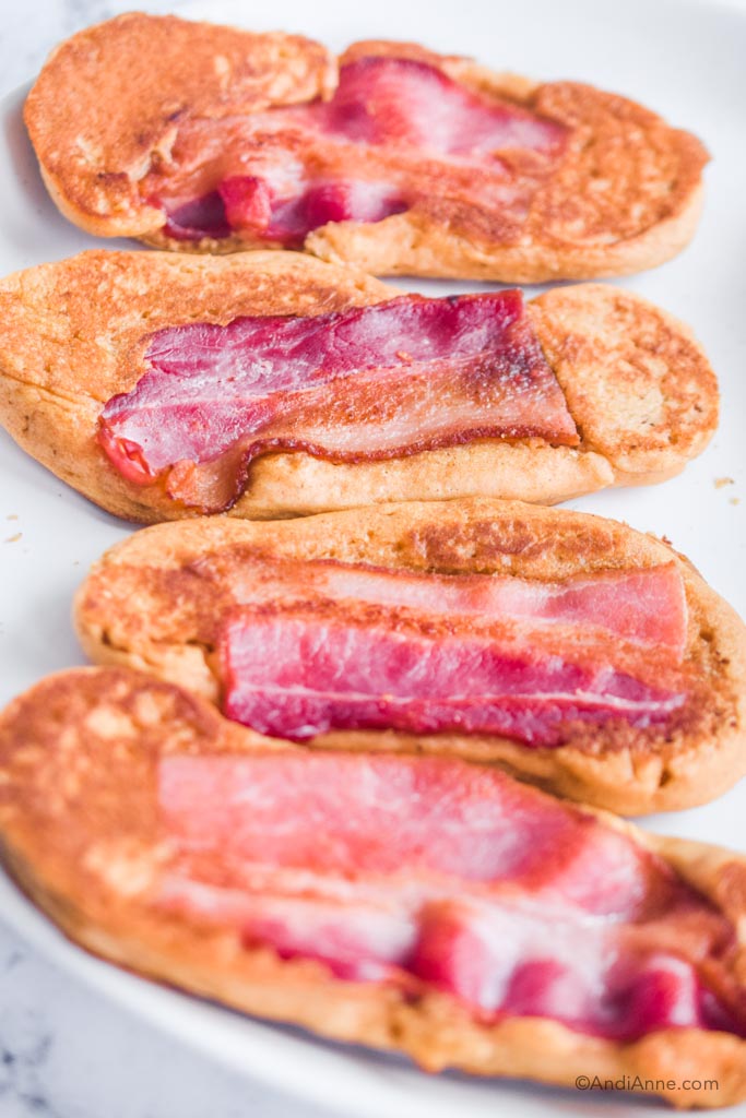 Four bacon pancakes on white surface.