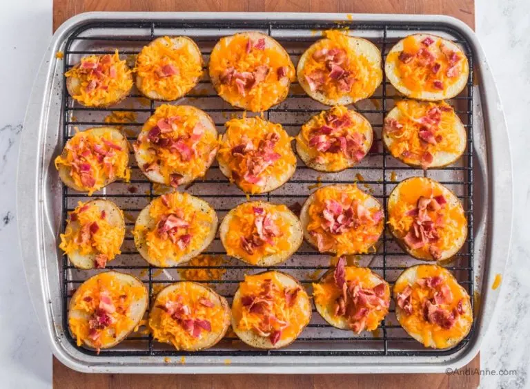 Melted cheese and bacon on top of potato slices on baking rack.