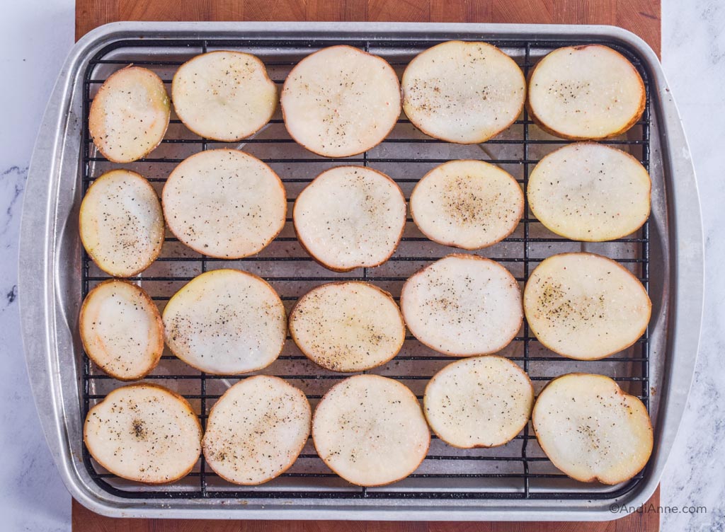 raw potato slices seasoned with salt and pepper on a baking rack.