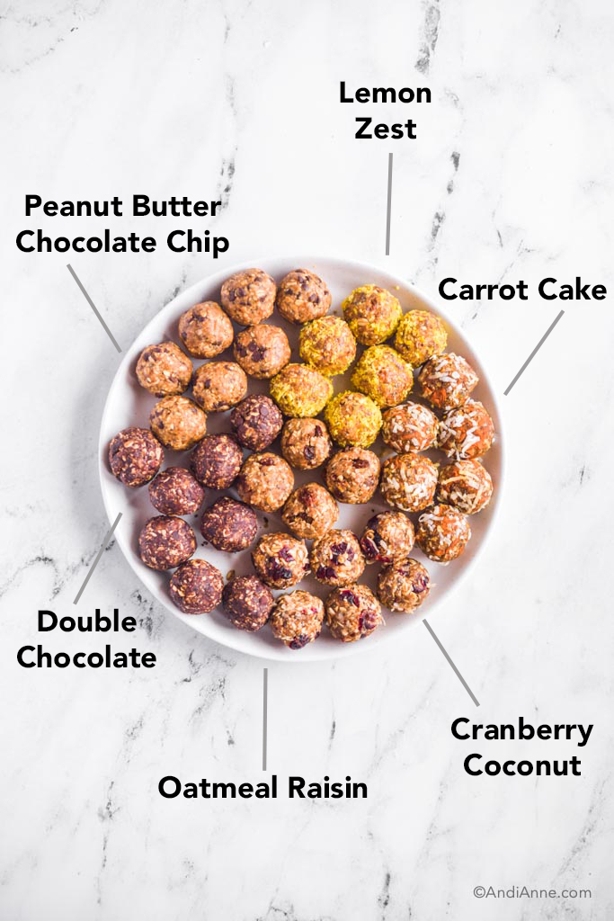 six energy ball flavors on large white plate: peanut butter chocolate chip, carrot cake, double chocolate, oatmeal raisin, and cranberry coconut.