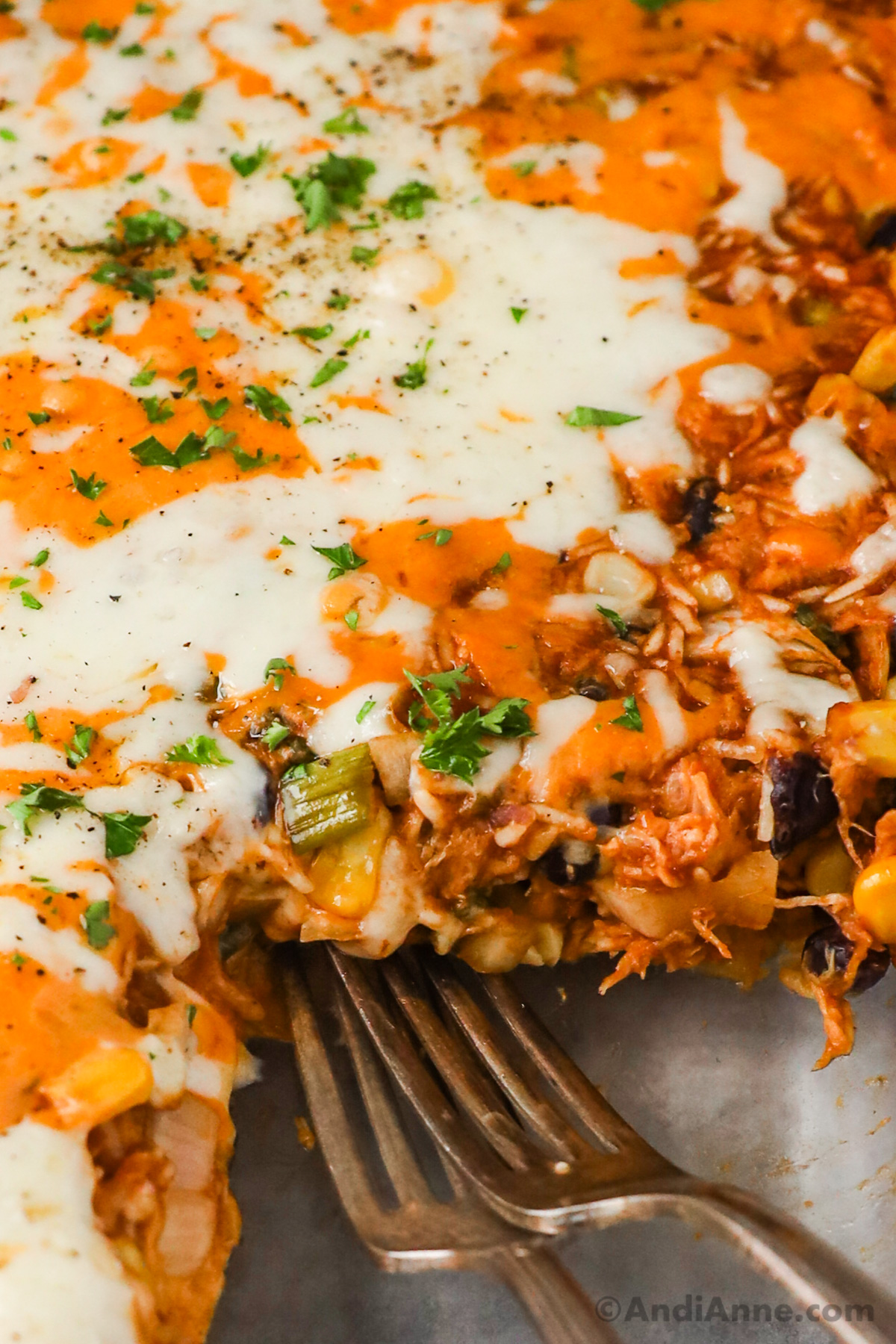 Close up of melted white and orange cheese on top of barbecue shredded chicken mixture with two forks