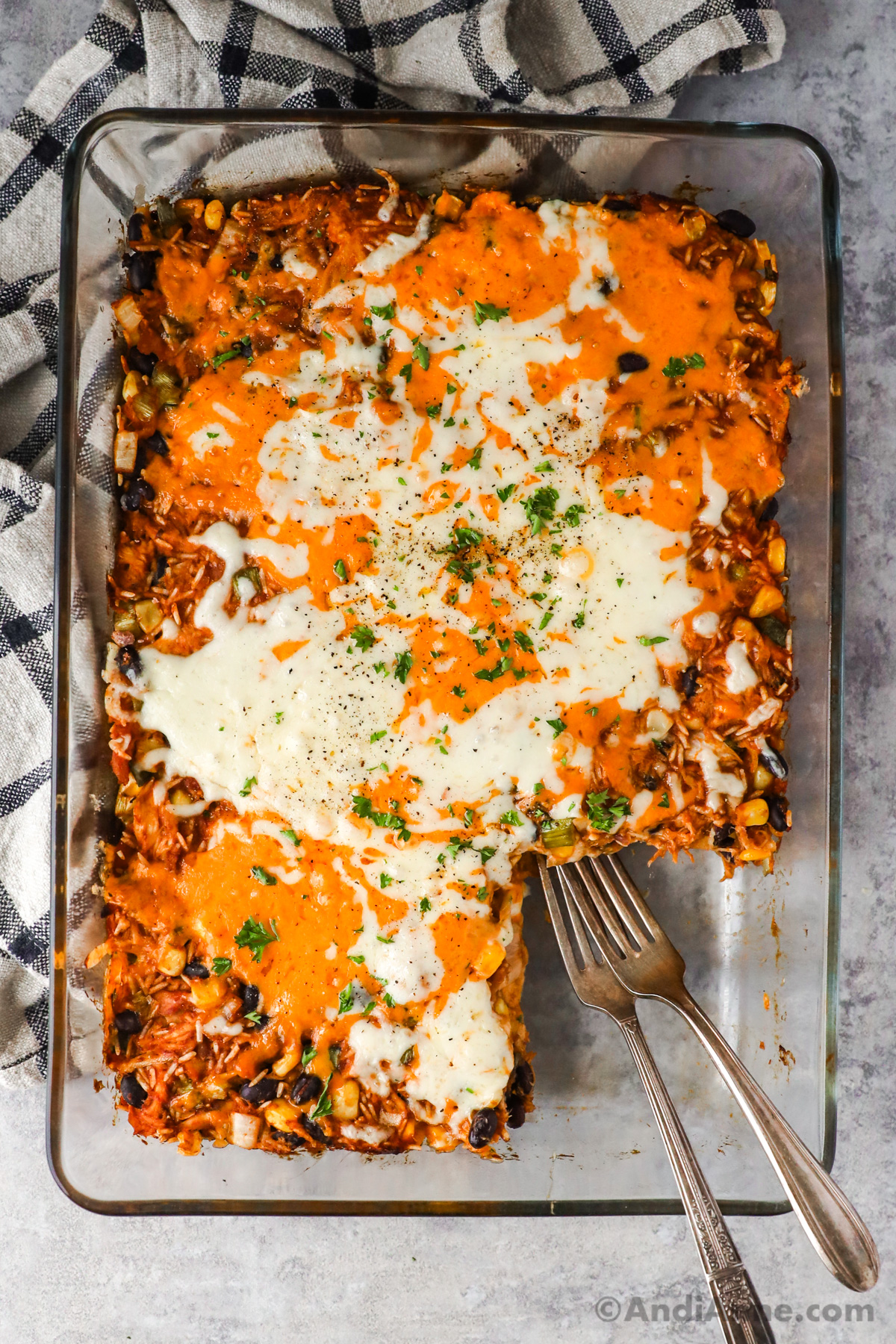 Shredded barbecue chicken casserole topped with melted cheese. Once slice cut out and two forks.