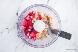 sliced strawberries, sliced banana, and milk in a food processor