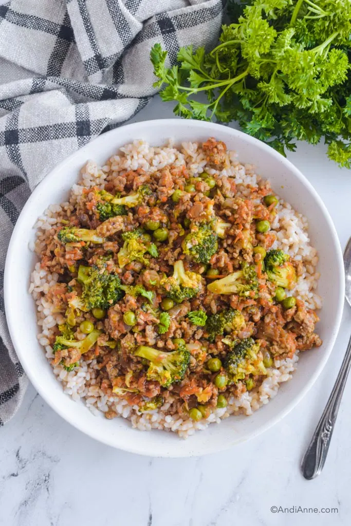 bowl of teriyaki ground turkey recipe with broccoli, shredded carrots and peas.