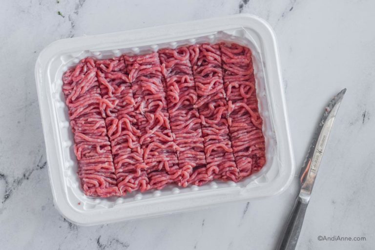 ground turkey in white plastic container with knife beside it