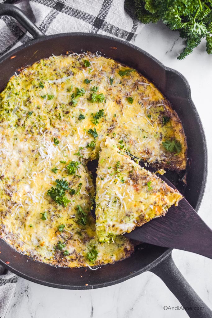 zucchini parmesan frittata in cast iron skillet with pie slice taken out on spatula