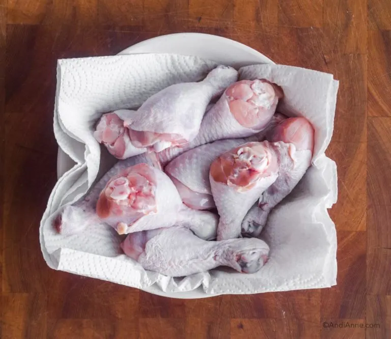 raw chicken drumsticks in bowl with paper towel