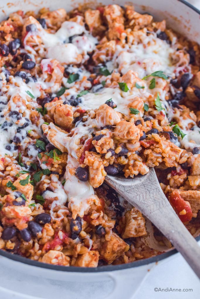 Close up of one pot chicken burrito bowl with wood spoon. 