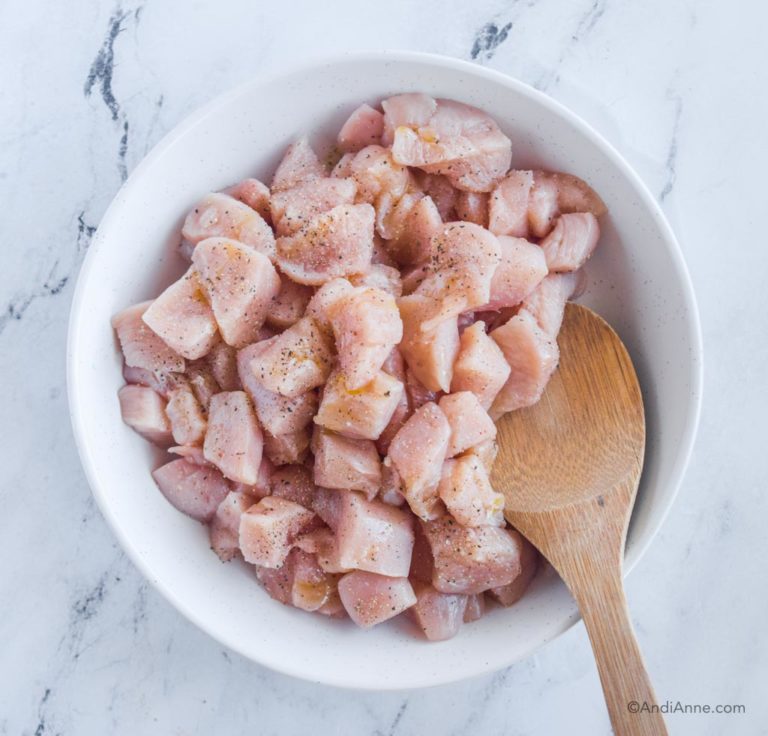 chopped raw chicken in a bowl with wood spoon